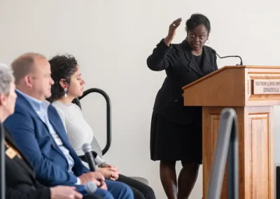 A speaker addresses a panel and audience from a Southern Illinois University Edwardsville podium during a formal presentation.